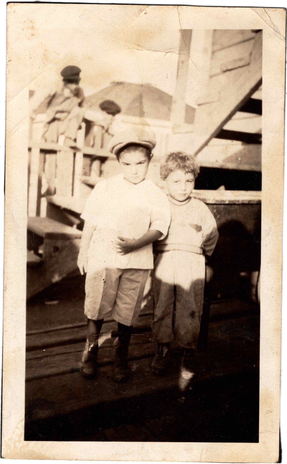 Two small boys, one in a flat cap, standing in a backyard, circa 1924