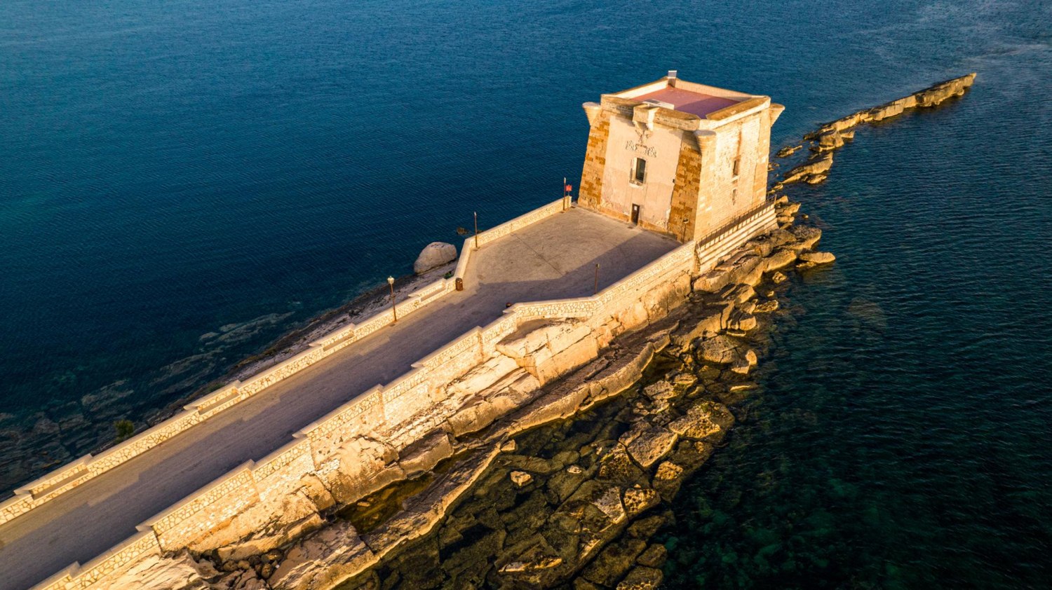 Aerial view of Torre di Ligny extending into the blue sea at Trapani
