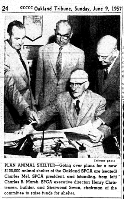 Charles Mel seated at a desk reviewing plans with three men standing behind him