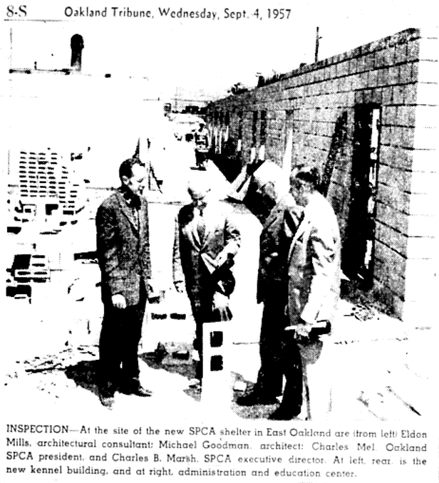 Four men inspecting a construction site beside a concrete block wall