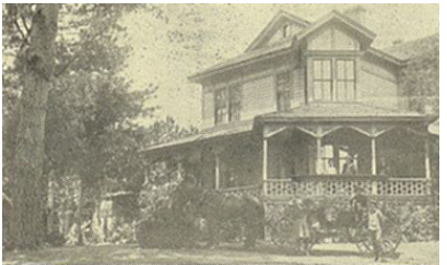 Two-story hotel with a wide veranda among trees, about 1905