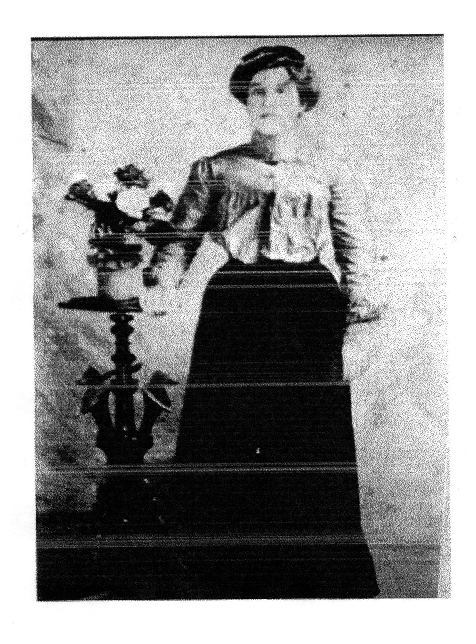 An early photograph of a young woman standing beside a pedestal