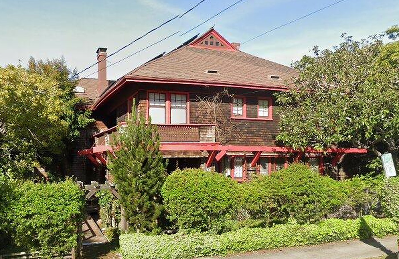 A brown-shingled Craftsman house with red trim at 1320 Arch Street, Berkeley, behind a clipped hedge