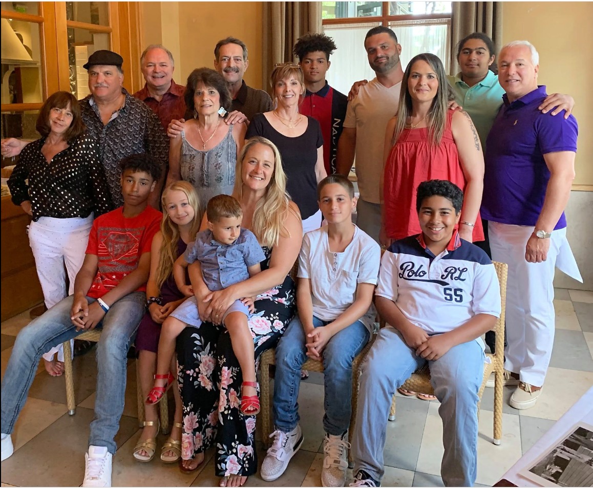 A large family group gathered for a photograph in a restaurant, adults standing behind children seated on chairs