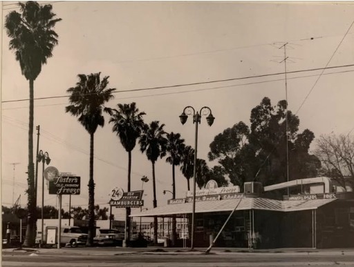 A roadside Foster's Old Fashioned Freeze stand with palm trees and parked cars