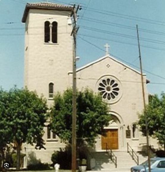 The front of Saint Peter Martyr Church, a pale stone building with a bell tower and rose window