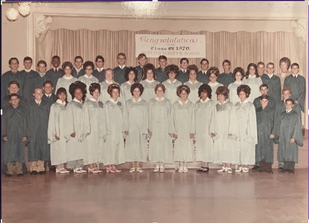 A graduating class in caps and gowns posed in rows on a stage beneath a Congratulations Class of 1970 banner