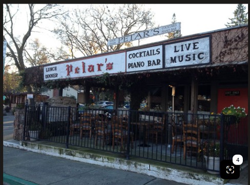 The street frontage of Petar's Restaurant, its signage reading Lunch, Dinner, Cocktails, Piano Bar and Live Music above a railed patio of tables