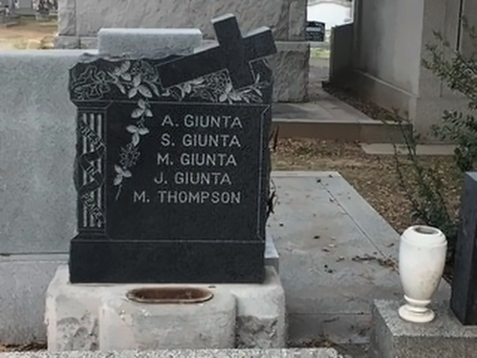 Black granite headstone carved with a cross and five family names