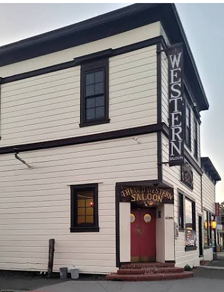 The white clapboard corner building of the Old Western Saloon with its vertical sign