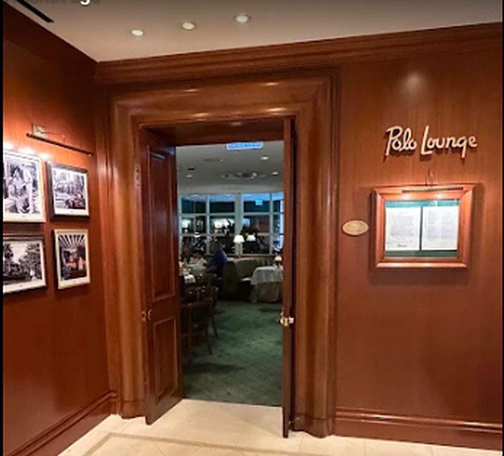 A panelled wooden doorway with the Polo Lounge name in script on the wall beside it